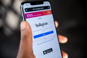 Foto di uno smartphone tenuto in mano che mostra sul display la pagina web di accesso a Instagram tramite browser mobile, usata per riferirsi al bisogno compulsivo di controllare i social che caratterizza chi soffre di dipendenza affettiva, tema di cui si occupa lo psicologo Alessio Congiu